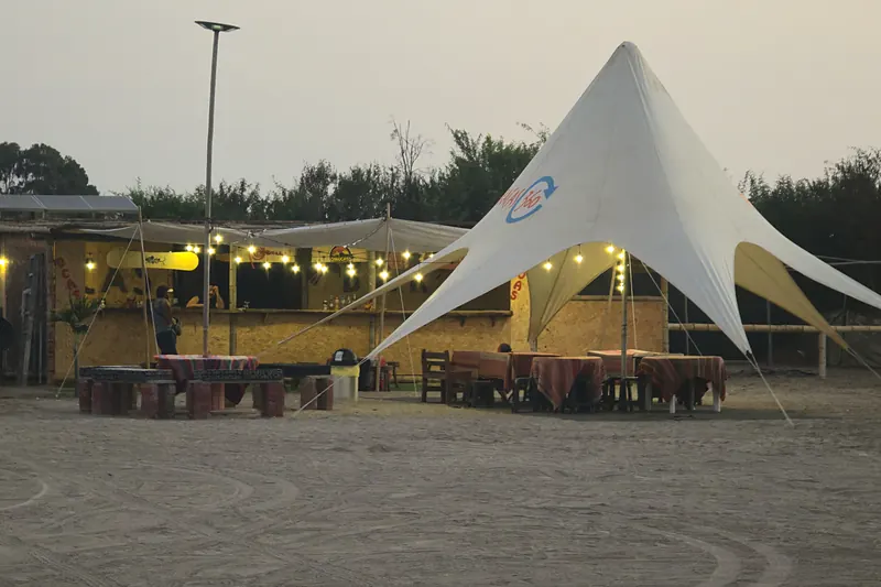 Toldo, mesas y zona de espera de la base al atardecer