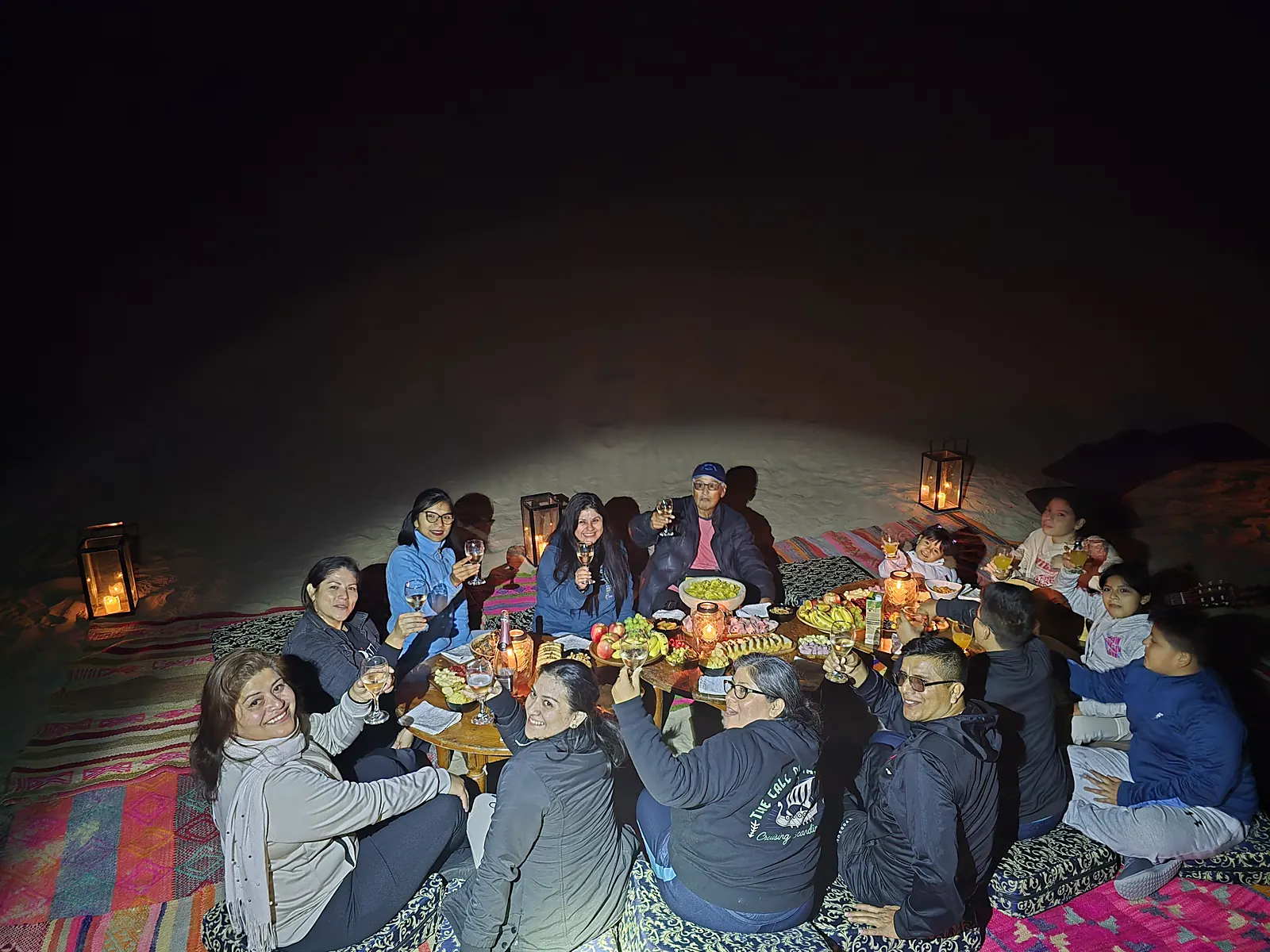 Grupo brindando de noche entre faroles en el desierto